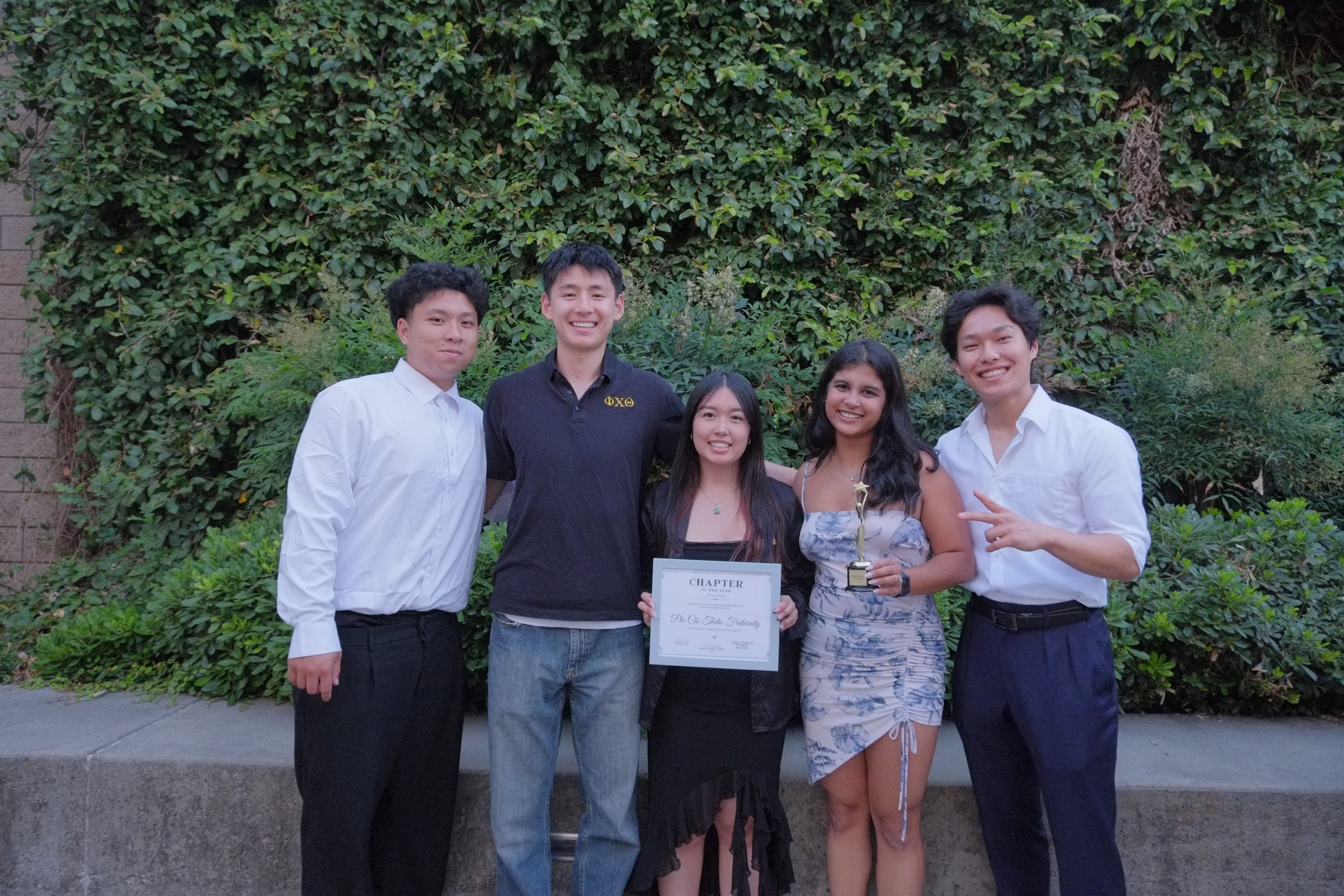 Five Phi Chi Theta members holding the Chapter of the Year award
